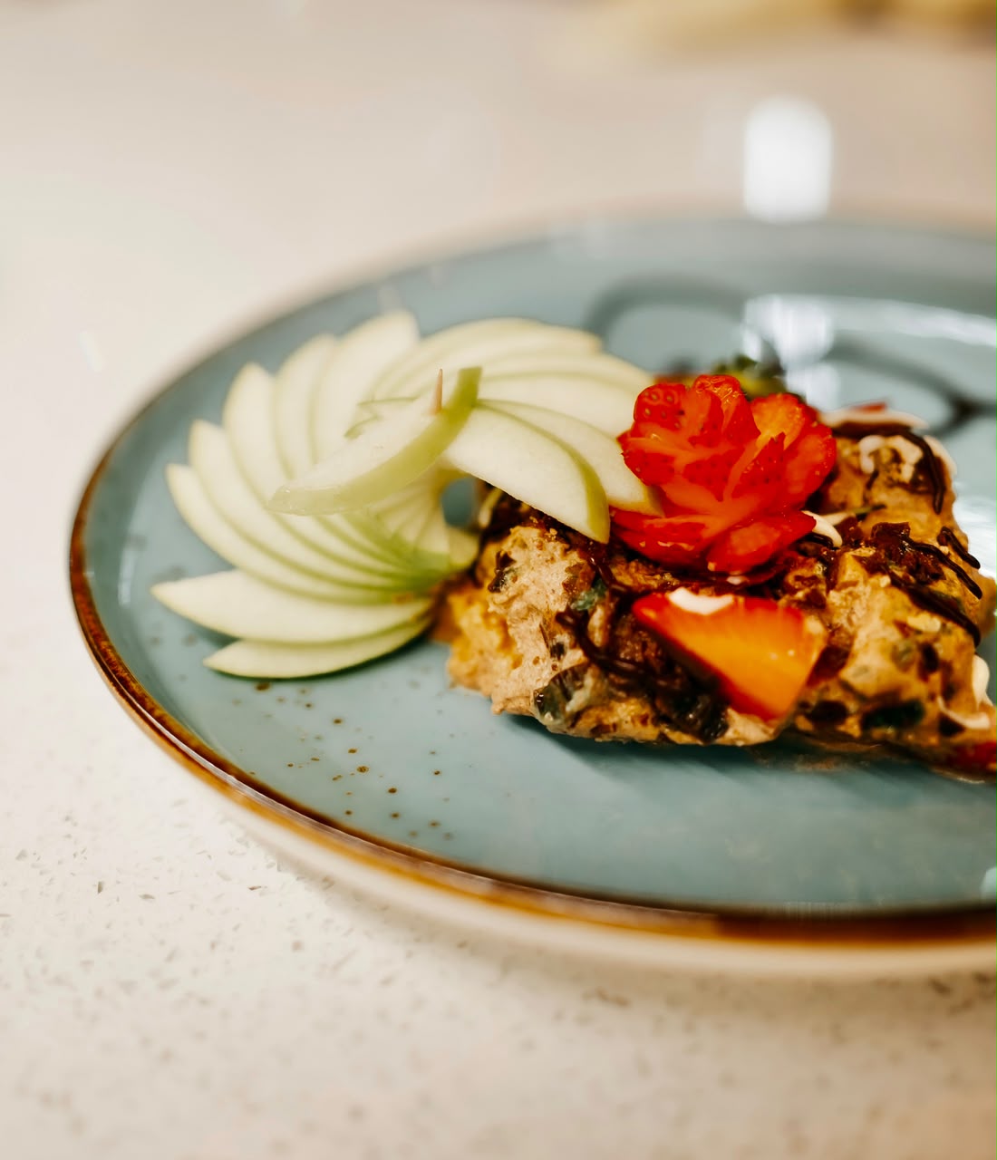 Omelette plated with fanned apple and a strawberry rose