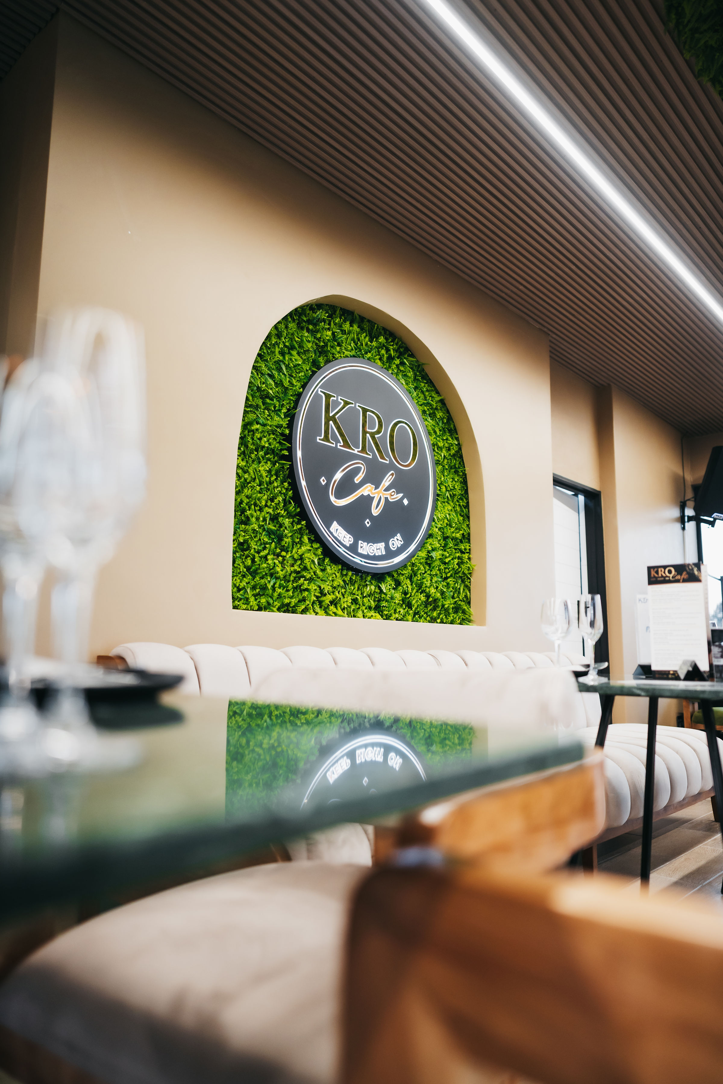 KRO Café interior with illuminated KRO logo, green feature wall and dining area