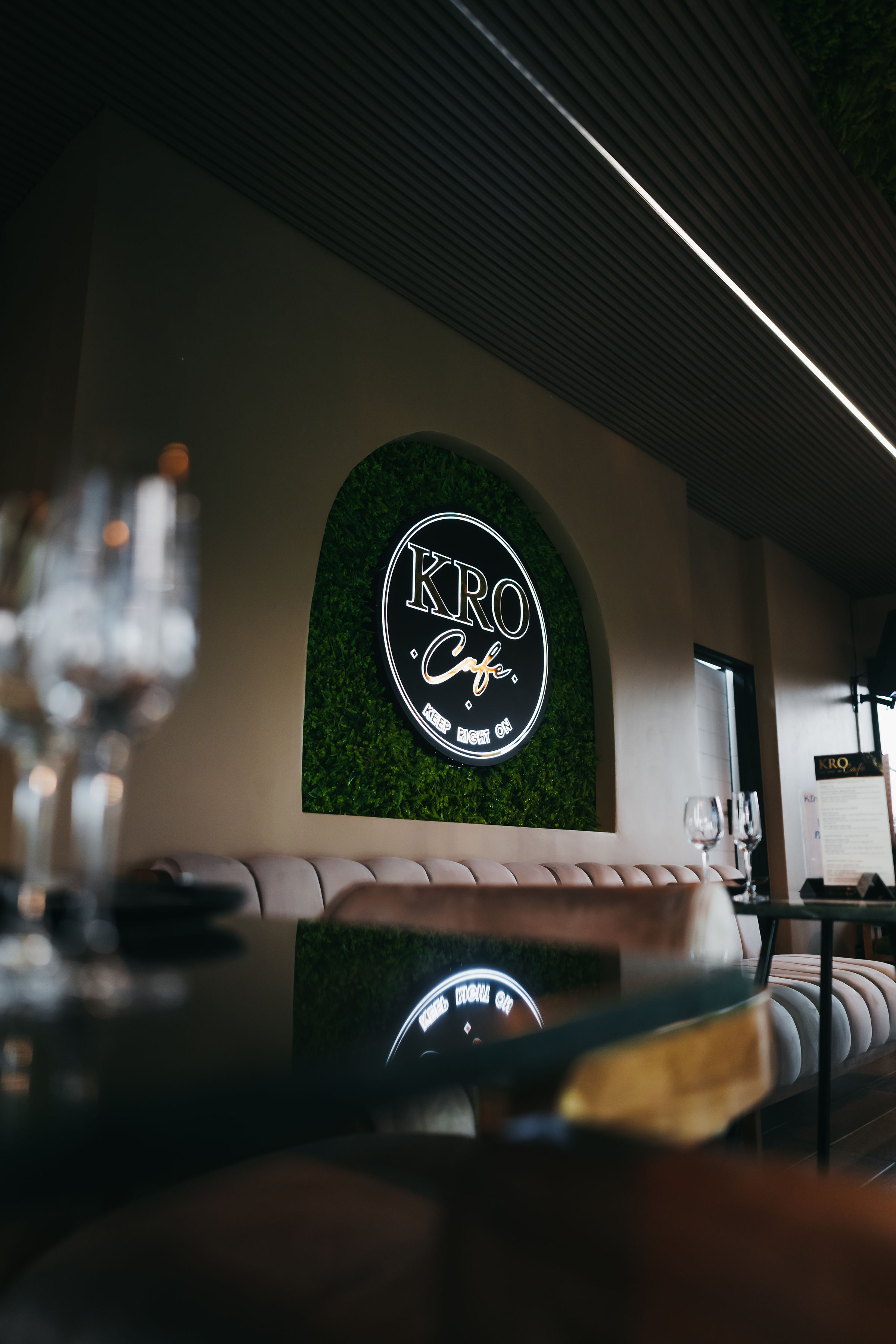 KRO Café interior with green feature wall, logo and warm dining room lighting