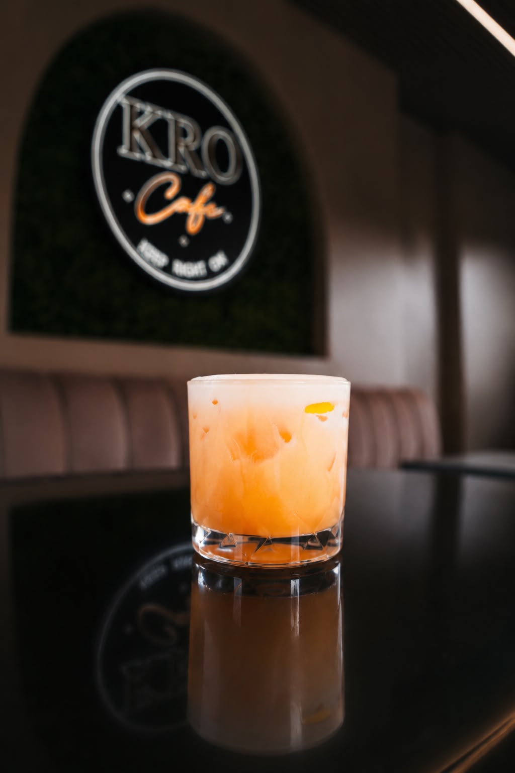 Orange cocktail in front of the KRO Café logo